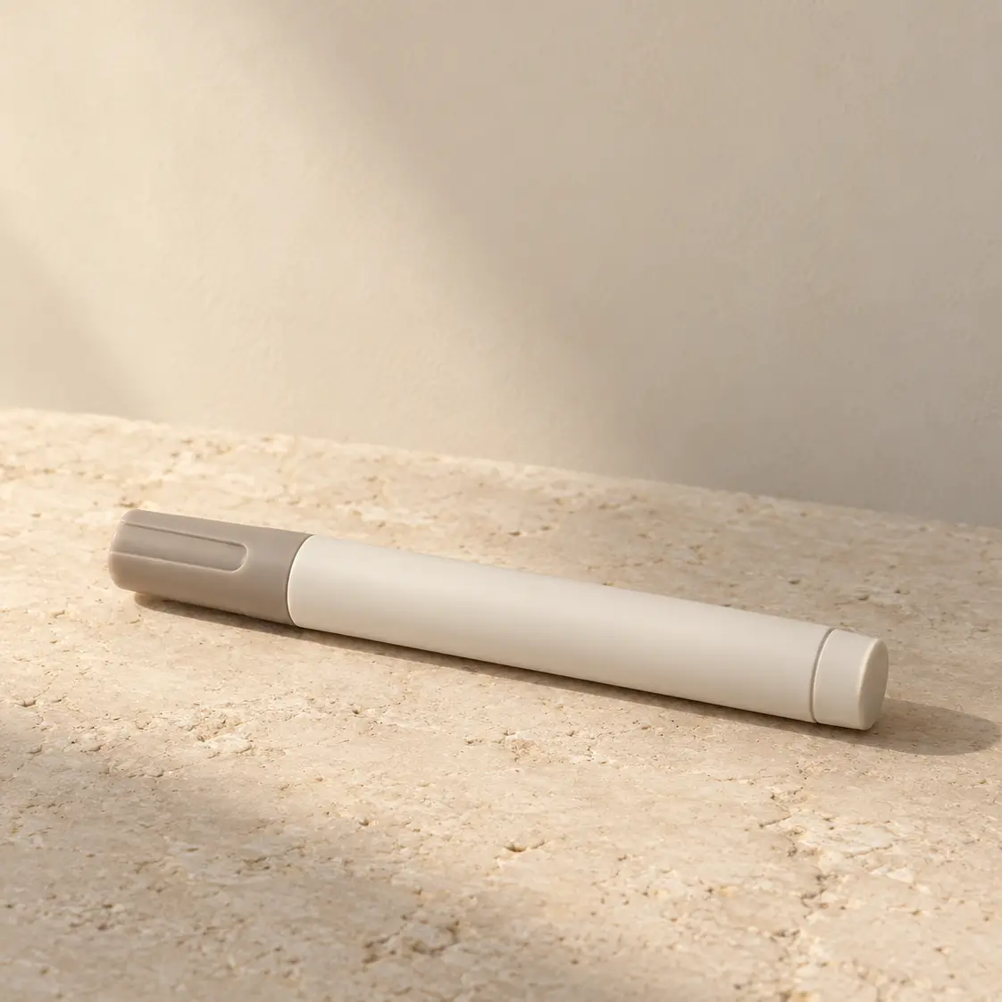 Unbranded injection pen on a warm limestone surface